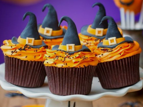 Orange cupcakes with witch hats on top of them